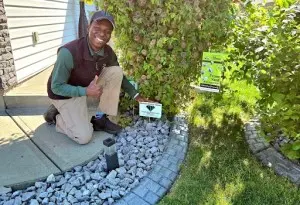Smiling Neighbourhood Heroes kneeling while placing service sign on rock bed