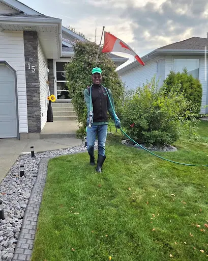 Smiling Neighbourhood Heroes technician applying weed control and fertilizer on lawn